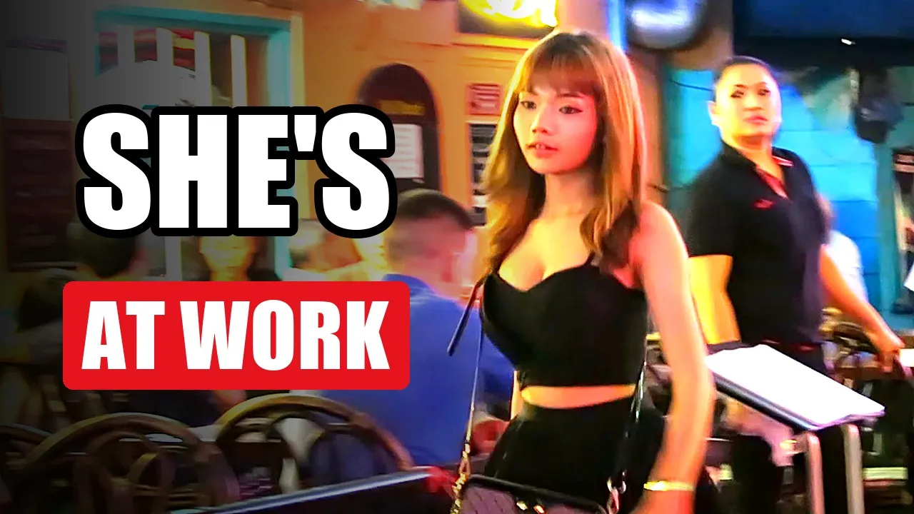 A bar in Thailand at night, with the words She's at work